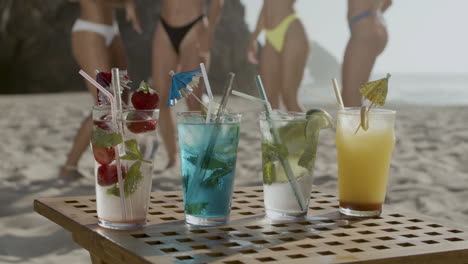 Cold-fruit-cocktails-in-glasses-with-straws-on-table-on-beach